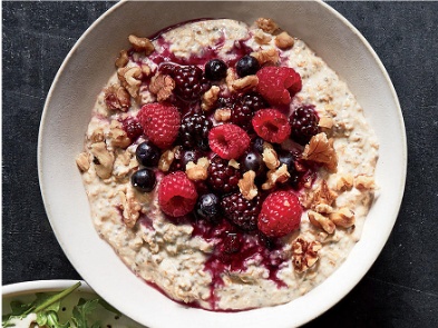 A bowl of oatmeal with fresh berries and nuts on top.