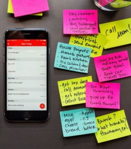 a desk with multiple post-its with various notes and a iPhone next to them.