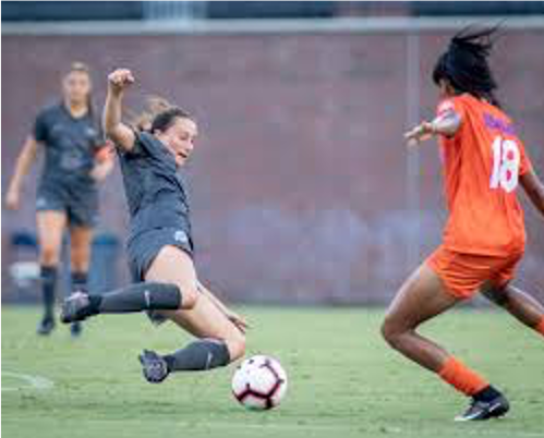 Two women playing soccer, both going for a ball to 'win' it from the other person. 
